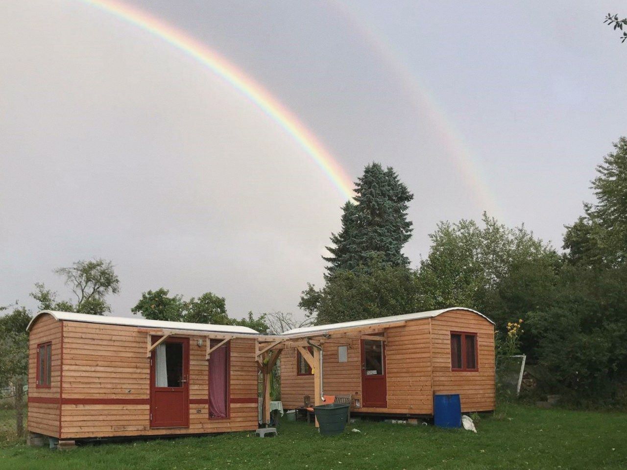 Zwei über Eck gestellte LandAnker auf einer Wiese, darüber ein Regenbogen