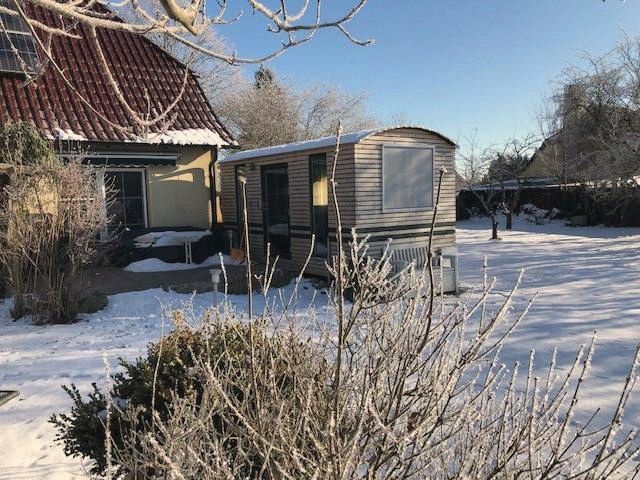 LandAnker im Schnee neben einem Wohnhaus, davor kahle Sträucher
