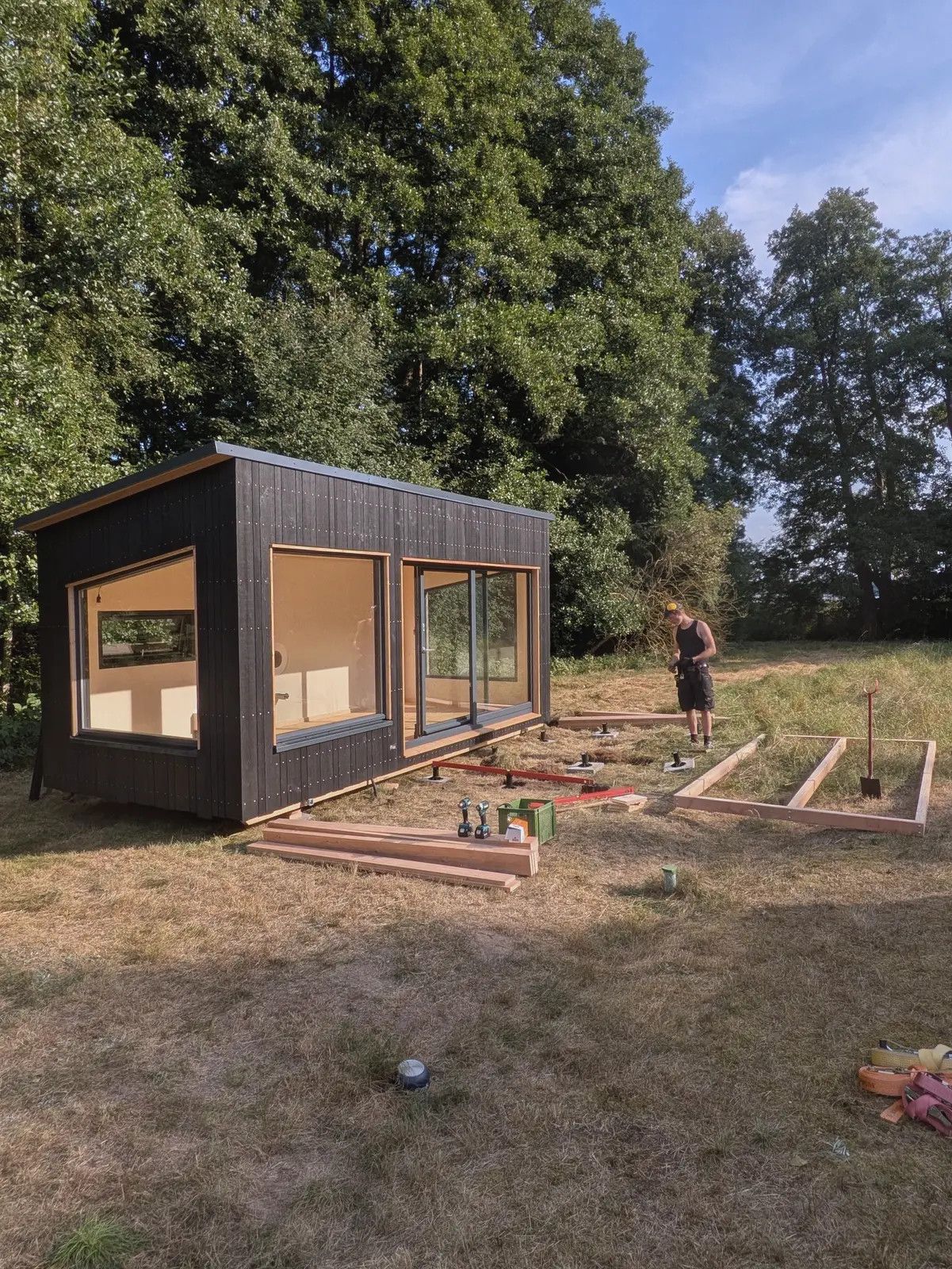 Schwarzer LandAnker mit Glasfront, davor liegt der Rahmen einer entstehenden Terrasse