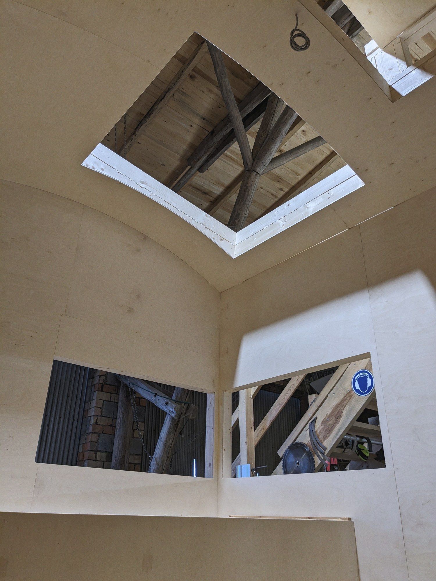 Blick von unten durch ein Dachfenster im Tonnendach auf den alten Dachstuhl der Scheune