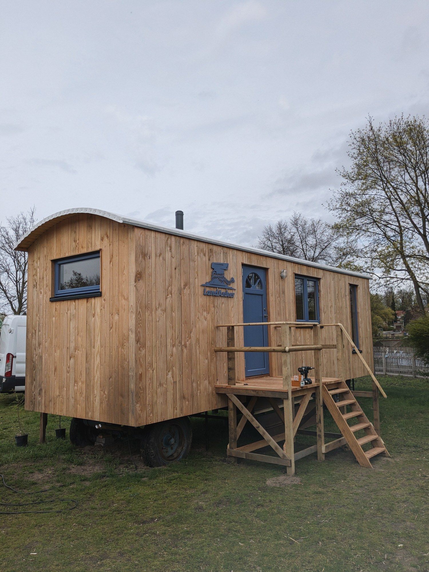 LandAnker mit blauer Tür, davor ein Holzpodest mit Treppe und Geländer