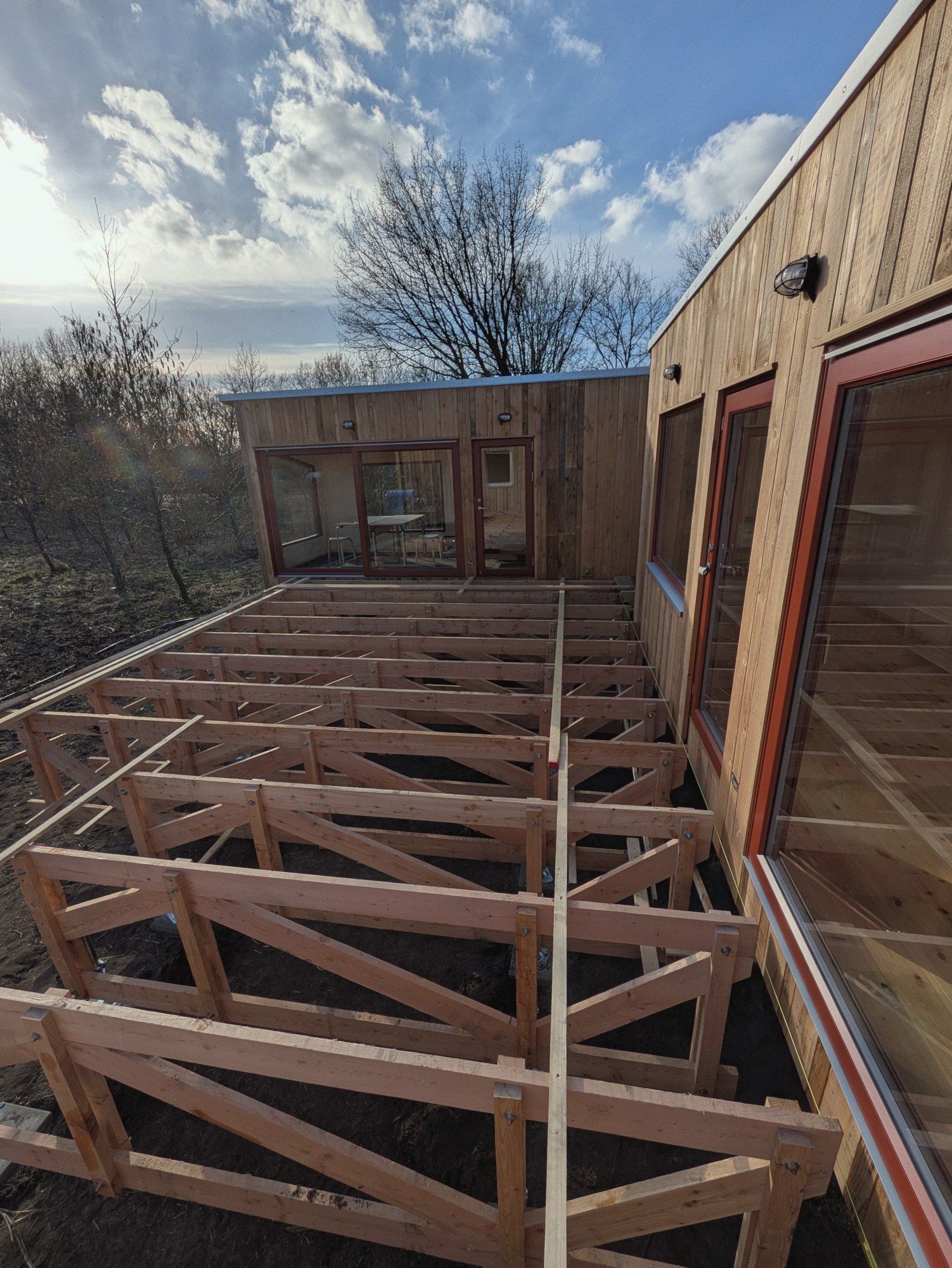 Unterkonstruktion einer großen Terrasse aus Holzbalken vor zwei LandAnkern, Gegenlicht