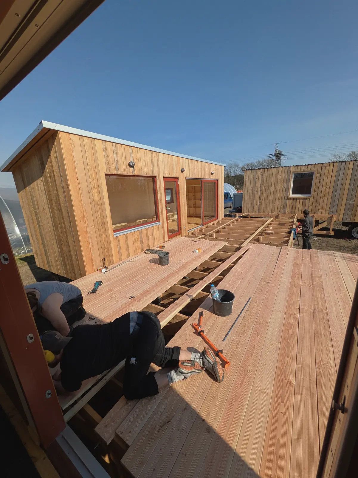 Zwei Handwerker verlegen Lärchendielen auf einer Terrasse vor einem LandAnker